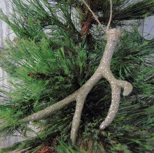 A glittery antler ornament hanging on a tree